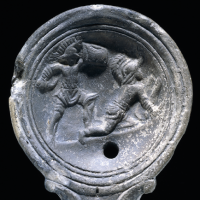 The top surface of a Roman clay lamp depicting two armed gladiators